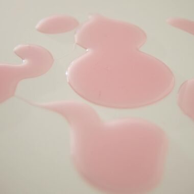 Abstract pink liquid pattern on a smooth white surface, ideal for backgrounds.