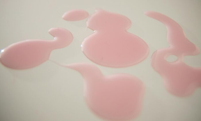 Abstract pink liquid pattern on a smooth white surface, ideal for backgrounds.