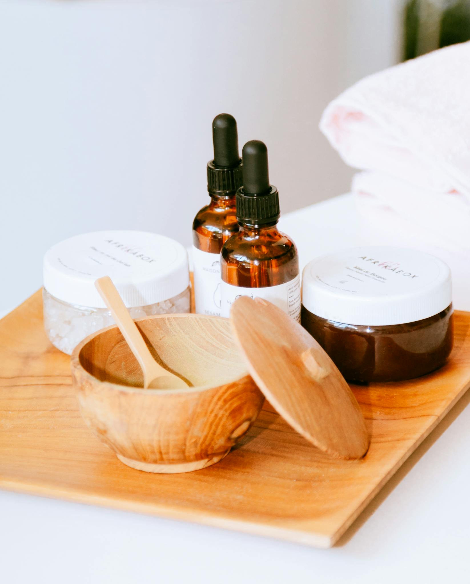 Aesthetic display of natural skincare products on a wooden tray with droppers and jars.