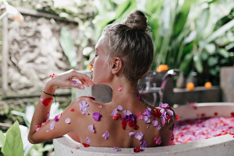 Pleased european woman doing spa with flower petals in weekend.