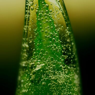 Macro shot of a green aloe vera gel bottle with visible bubbles, emphasizing freshness.