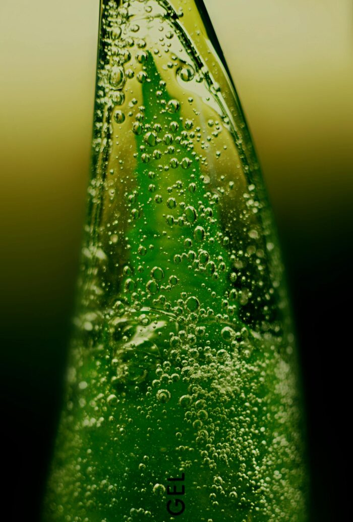Macro shot of a green aloe vera gel bottle with visible bubbles, emphasizing freshness.
