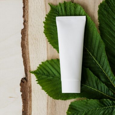 Top view of chestnut green leaf and mockup of skin care or hair care cosmetic product placed on wooden surface